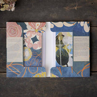 Open book with floral and abstract designs on a wooden surface